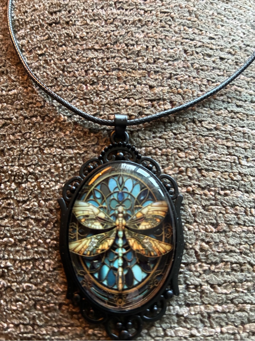 Dragonfly pendant in a domed setting, black filigree cameo accent. Cord is 17”